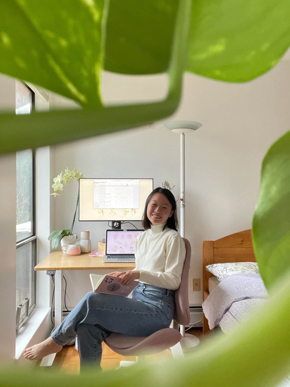 carol sitting at her computer with a notebook in her hand turned around in her chair smiling